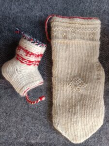 en stickad tumvante i vitt med mönster i vitt och en halv socka med hälstickning vänd ut och in